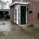 Een huis met een groene deur en een boom ervoor.