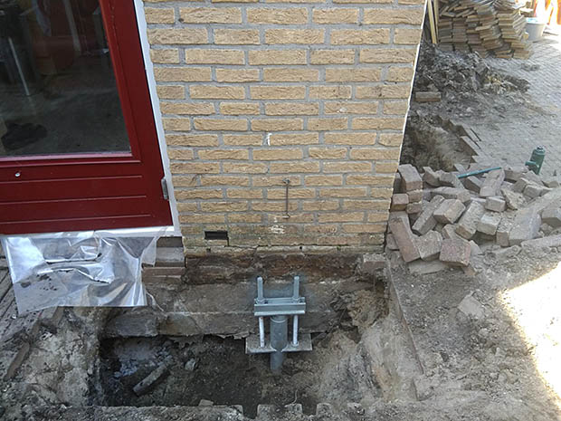 DFH paal in de grond onder de woning naast de rode deur