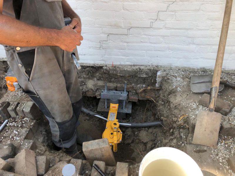 Een man werkt aan een gat in de grond bij een verzakking in een huis in Haarsteeg in Nederland.